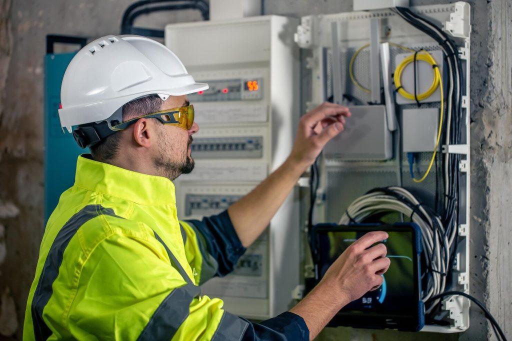 man electrical technician working switchboard with fuses uses tablet 169016 24053